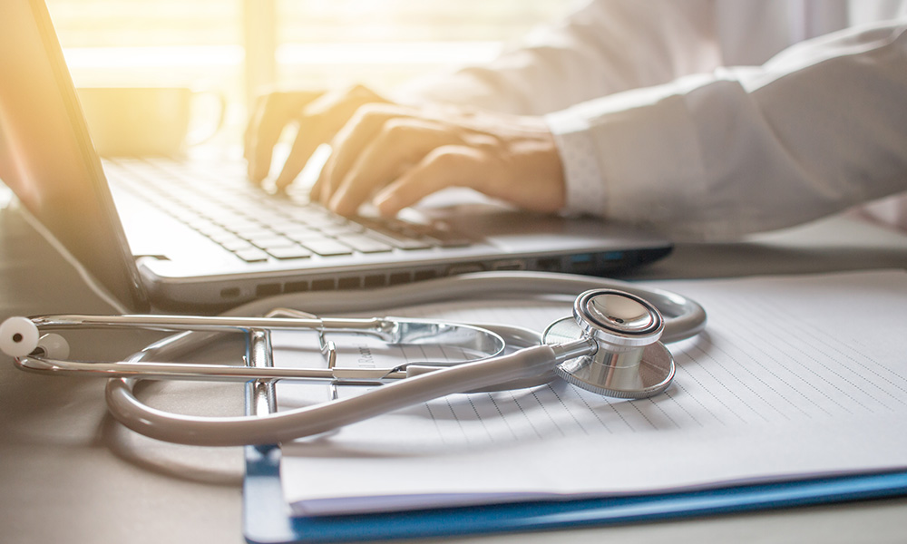 Blog - Doctor Typing on a Laptop By a Window on a Nice Day
