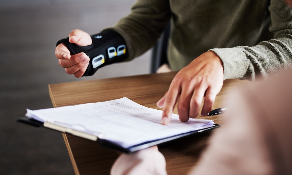A Smarter Workers’ Comp Solution for Staffing Firms - Injured worker sitting at a desk going over a form
